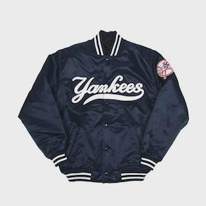 Può includere: Giacca da baseball dei Yankees in raso blu navy con scritte e finiture bianche. Presenta una chiusura con bottoni, una toppa con il logo della squadra sulla manica e dettagli a righe sul colletto, sui polsini e sull'orlo.