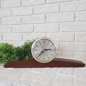 May include: A white ceramic mug with a black handle and the text "But First, Coffee" in a black, bold font. The mug is sitting on a wooden surface. The mug is approximately 4 inches tall.