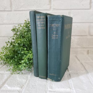 May include: Two dark green hardcover books standing upright. The left book is titled Theodore Roosevelt's Letters to His Children with Scribners at the bottom. The right book is titled Marching On by James Boyd with Scribners at the bottom.