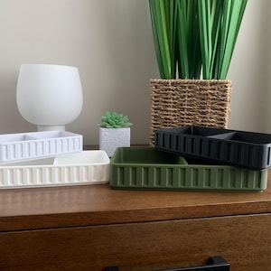 Puede incluir: Bandejas rectangulares de almacenamiento en blanco, crema, verde oliva y negro. Cada bandeja tiene un interior dividido y un exterior acanalado. Adecuado para la organización del hogar.