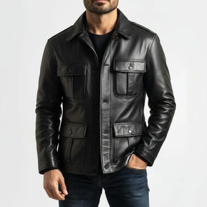 May include: Black leather jacket featuring four front pockets, a button-up front, and a collared neckline. The jacket is worn over a black top and paired with blue jeans. The jacket has a classic, tailored design.