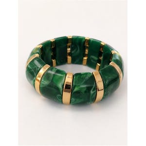 May include: A chunky bracelet featuring rectangular green marbled segments with gold-colored metal accents. The bracelet is a bold statement piece, perfect for adding a touch of color and style to any outfit. The bracelet is approximately 2 inches in diameter.