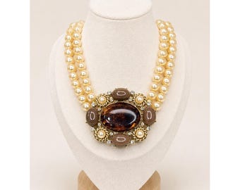 Collar vintage de doble hebra con perlas de imitación y un gran cabujón en tono dorado.