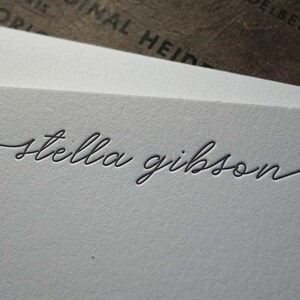 May include: A white card with the name "stella gibson" written in cursive script.