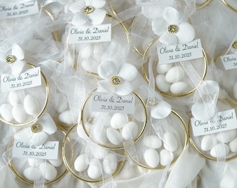 Recuerdos de boda personalizados de almendras, envueltos en tul, con decoración de anillo dorado.