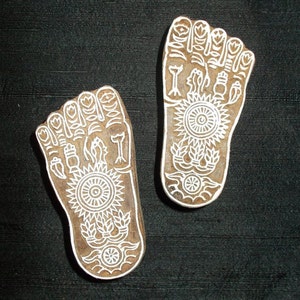 Puede incluir: Dos estampados de madera de pies descalzos con intrincados diseños blancos. Los diseños incluyen flores, hojas y formas geométricas.