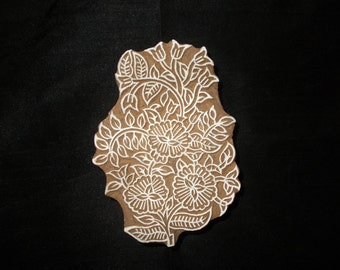 May include: A wooden block printing stamp with a white floral design. The design features intricate details of leaves and flowers.