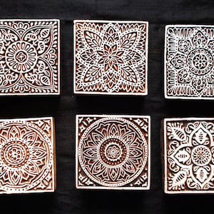 Puede incluir: Seis bloques de impresión de madera con intrincados diseños florales. Los bloques son cuadrados y tienen un color marrón claro. Están dispuestos en dos filas de tres.