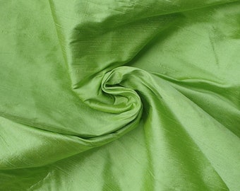 May include: A close-up of a smooth, green fabric with a silky texture. The fabric is folded and draped, showcasing its soft and flowing nature.