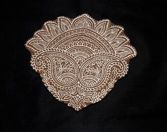 May include: A white, intricate paisley design on a brown background. The design is symmetrical and features a floral motif.