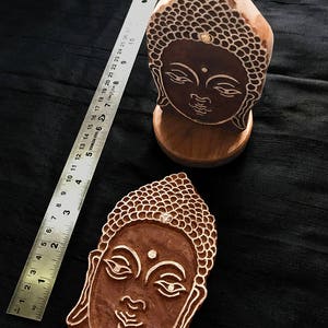 May include: Two wooden Buddha head printing blocks. The blocks are carved with intricate details and have a natural wood finish.