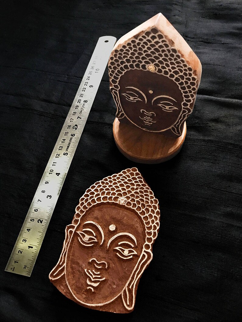 May include: Two wooden Buddha head printing blocks. The blocks are carved with intricate details and have a natural wood finish.