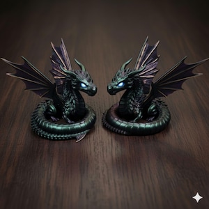 Pu&ograve; includere: Due dettagliate statuette di drago. Ogni drago &egrave; verde scuro con ali nere e occhi blu luminosi. I draghi sono arrotolati e si trovano su una superficie di legno scuro. Le ali sono spiegate e i draghi si guardano.
