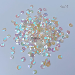 May include: A collection of small, circular, iridescent sequins with a central hole. The sequins feature a translucent, pearlescent finish that reflects light in various colors. The text 4m and Chinese characters with the word Workshop are visible.