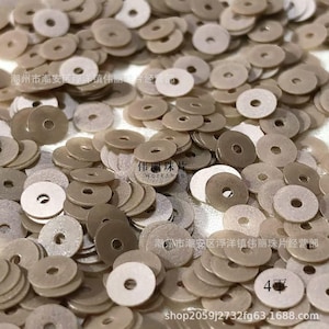 Op de afbeelding: Een stapel beige, cirkelvormige kralen met een gat in het midden. De kralen zijn verspreid, met verschillende tinten beige en gebroken wit. De afbeelding bevat Chinese tekst en het nummer "4".