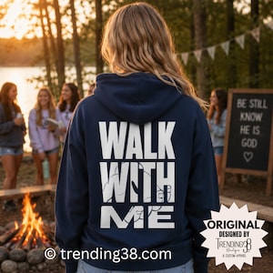 Könnte beinhalten: Ein marineblauer Kapuzenpullover mit dem weißen Schriftzug WALK WITH ME auf der Rückseite. Das Design enthält eine Grafik von zwei Händen, die innerhalb der Buchstaben aufeinander zu greifen. Der Hoodie hat eine Kapuze mit Kordelzug und lange Ärmel.