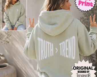 May include: A sage green hooded sweatshirt featuring a white puff print on the back that reads TRUTH > TREND. The front chest area displays a small white chevron graphic, and the sleeves feature matching chevron details in a puff print finish.