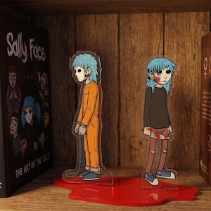 May include: Two acrylic character standees featuring a blue-haired figure. One wears an orange jumpsuit with chains, the other a dark shirt and red pants with a bloodied knife. They stand on a red base shaped like a pool of blood.