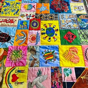Può includere: Una colorata trapunta patchwork composta da numerosi quadrati di tessuto, ognuno con disegni ricamati unici. I quadrati presentano vari motivi, tra cui pesci, tartarughe e motivi astratti, in una vivace gamma di colori. La trapunta è di forma rettangolare.