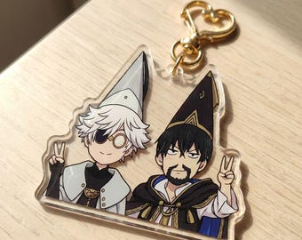 May include: A clear acrylic keychain featuring two illustrated characters wearing pointed hats and making peace signs. The character on the left has white hair and a monocle, while the character on the right has black hair and a beard. Gold heart clasp.