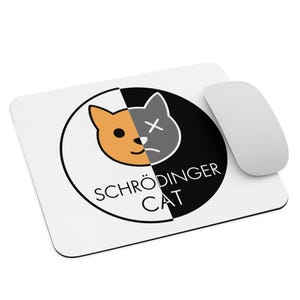 Könnte beinhalten: Weißes rechteckiges Mauspad mit einem schwarz-weißen kreisförmigen Design mit einem in zwei Hälften geteilten Katzenkopf, eine Seite orange, die andere grau. Der Text "SCHRÖDINGER CAT" steht darunter. Eine weiße Computermaus liegt daneben.