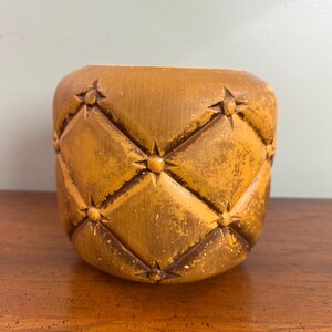 May include: A white ceramic mug with a black handle and the text "But First, Coffee" in a bold, black font. The mug is set against a blurred background, suggesting a cozy setting. The mug appears to be approximately 4 inches tall.