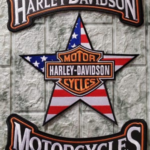 Puede incluir: Un conjunto de tres parches bordados con el logotipo de Harley-Davidson en negro y naranja. Los parches superior e inferior son curvos con texto en blanco, mientras que el parche central es una estrella con un patrón de bandera de EE. UU.