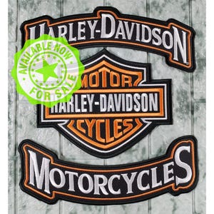 May include: Three embroidered patches featuring the Harley-Davidson logo. The top arch reads Harley-Davidson in white. The center shield displays Motor Harley-Davidson Cycles in orange and white. The bottom arch reads Motorcycles in white.