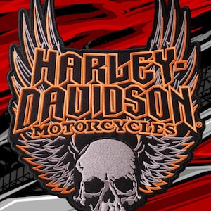 May include: A black, orange, and grey embroidered patch featuring the text Harley-Davidson Motorcycles in orange lettering. The design includes a central grey skull graphic flanked by large, detailed wings extending upwards and downwards.