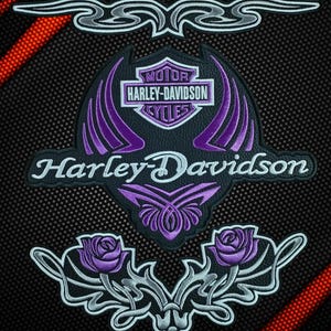 Puede incluir: Un conjunto de parches bordados negros que incluye un logotipo de escudo Harley-Davidson con detalles en morado, el texto Harley-Davidson en letra blanca, dos rosas moradas con filigrana plateada y un adorno tribal plateado separado.