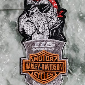 May include: Embroidered patch featuring a dog wearing sunglasses and a red bandana. The patch includes the Harley-Davidson logo with the text "MOTOR HARLEY-DAVIDSON CYCLES SINCE 1903" and "115 years".