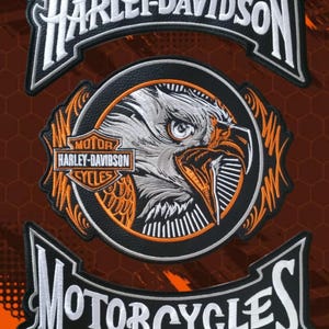 Pode incluir: Patches bordados para motocicletas Harley-Davidson. Os patches apresentam o logotipo Harley-Davidson, a palavra "MOTORCYCLES" e um design detalhado de águia em branco, laranja e preto. O fundo é laranja com um padrão de favo de mel.