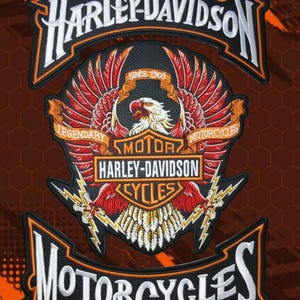 Puede incluir: Un parche bordado grande de Harley-Davidson que presenta un águila central con las alas extendidas, plumas rojas y blancas y rayos amarillos. El diseño incluye el texto Harley-Davidson, Motor Cycles y Since 1903 en naranja y blanco.