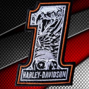 Puede incluir: Un parche bordado en negro, blanco y naranja con la forma del número uno. El diseño presenta una cabeza de águila detallada en la parte superior y el texto HARLEY-DAVIDSON en letras mayúsculas blancas en la base, con un borde negro grueso.