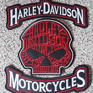 May include: A three-piece embroidered patch set featuring a top rocker with white Harley-Davidson text, a bottom rocker with white Motorcycles text, and a central skull-shaped patch with red Harley-Davidson Motorcyles Co. Est. 1903 text.