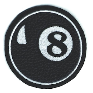 Puede incluir: Un parche redondo negro con un diseño de bola de billar número 8 blanco. El número 8 está en el centro, con un contorno blanco. El parche tiene una apariencia texturizada y un borde cosido blanco.