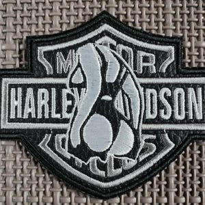 May include: Black and white Harley-Davidson patch with embroidered text and a shield design. The patch features the words "HARLEY-DAVIDSON" and "MOTOR CYCLES" in white lettering, with a stylized graphic in the center.