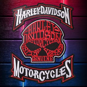 May include: A Harley-Davidson patch with the brand's logo and a skull design. The patch has a black background with red and white lettering. The words "Harley-Davidson" and "Motorcycles" are prominently displayed.