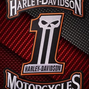 Könnte beinhalten: Ein Set aus drei bestickten Aufnähern mit dem Harley-Davidson-Logo. Die oberen und unteren Aufnäher sind geschwungen, mit weißem Text auf schwarzem Hintergrund und orangefarbenen Rändern. Der mittlere Aufnäher zeigt eine große Eins mit Totenkopf.