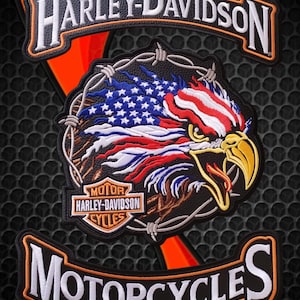 以下が含まれることがあります： 上部にHarley-Davidson、下部にMotorcyclesの白い文字とオレンジの縁取りが施された3ピースの刺繍ワッペンセット。中央のワッペンには、星条旗柄の羽を持つハクトウワシと有刺鉄線が描かれています。