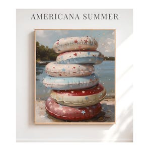 May include: A framed print featuring a stack of six colorful inflatable pool rings. The rings are decorated with stars and patterns in red, white, and blue, evoking a patriotic summer theme. The text "AMERICANA SUMMER" is at the top.