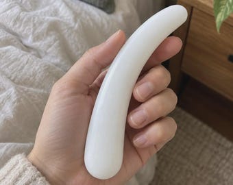 May include: A smooth, solid white curved object with a rounded tip and a cylindrical, tapered body. The item features a glossy, opaque finish and a simple, ergonomic shape that fits comfortably within the palm of a hand.