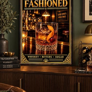 K&ouml;nnte beinhalten: Ein rechteckiges gerahmtes Wandbild mit einem Glas Old Fashioned Cocktail, garniert mit einer Orangenzeste und einer Kirsche. Der Text lautet OLD FASHIONED oben und WHISKEY &bull; BITTERS &bull; SUGAR unten, vor einem Bar-Hintergrund.