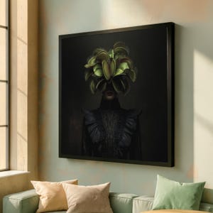 May include: A framed art print featuring a person with a Venus flytrap headdress. The person is wearing a black ruffled garment against a dark background. The flytrap is green and yellow.