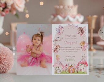 May include: A pink and white unicorn figurine with a golden horn and pink mane sits next to a card with a baby girl's photo and text that reads "Fairy First". The scene includes a cake, balloons, and flowers.