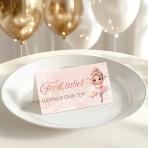 May include: A pink food label with the text "Food label" and "ADD YOUR OWN TEXT". The label features a cartoon ballerina in a pink tutu. The label is on a white plate with gold and white balloons in the background.
