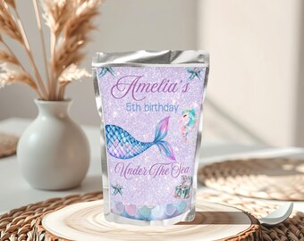 May include: A stand-up pouch with a mermaid theme. The pouch is lavender with the text "Amelia's 5th birthday" and "Under The Sea". A mermaid tail, seahorse, and other sea-themed graphics are featured on the front.