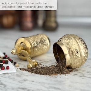 May include: A gold-colored spice grinder with intricate embossed patterns, with ground spices spilling out. The text in the image reads: "Add color to your kitchen with the decorative and traditional spice grinder."