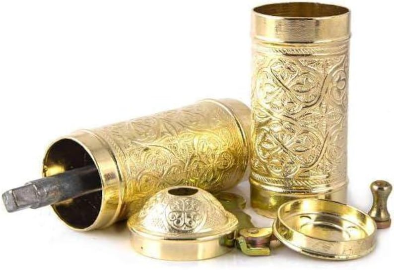 Pode incluir: Um conjunto de componentes de moedor de especiarias de metal dourado ornamentado. As pe&ccedil;as incluem um corpo cil&iacute;ndrico, uma base, uma tampa e uma al&ccedil;a. As superf&iacute;cies s&atilde;o decoradas com um padr&atilde;o floral em relevo. O moedor foi projetado para ser montado.