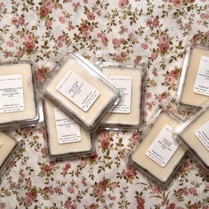 May include: A collection of rectangular wax melts in clear plastic clamshell containers, each featuring a white label with the text 'COBL CANDLE CO.' and specific scent names like 'Marshmallow Fireside', 'Frosted Plum', 'Chai Latte', and 'Brown Sugar & Fig'.